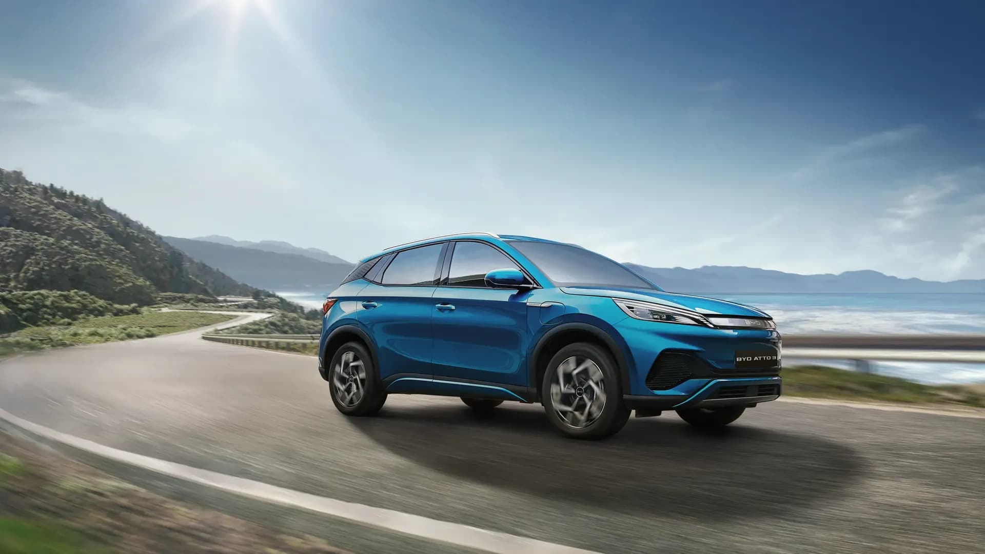 BYD ATTO 3 warna Surf Blue melaju di jalan pesisir pegunungan